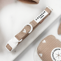 Beige ribbed dog collar with white heart pattern and a white plastic buckle.