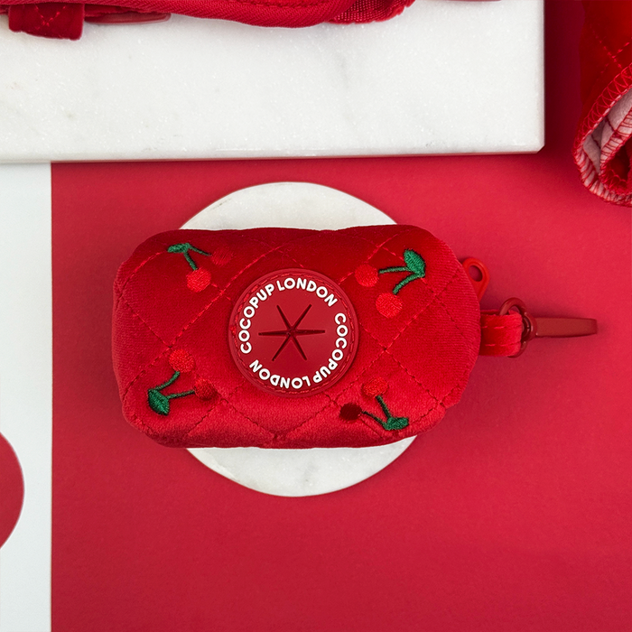 Quilted red velvet poop bag holder with embroidered cherry design.