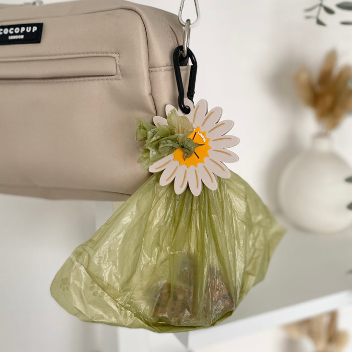 Daisy-patterned Cocopup CocoPOOP Pocket with black clip attached to a beige bag.