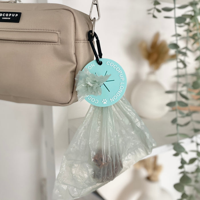 Beige dog walking bag with mint CocoPOOP Pocket by Cocopup London hanging on a hook, holds a used waste bag.