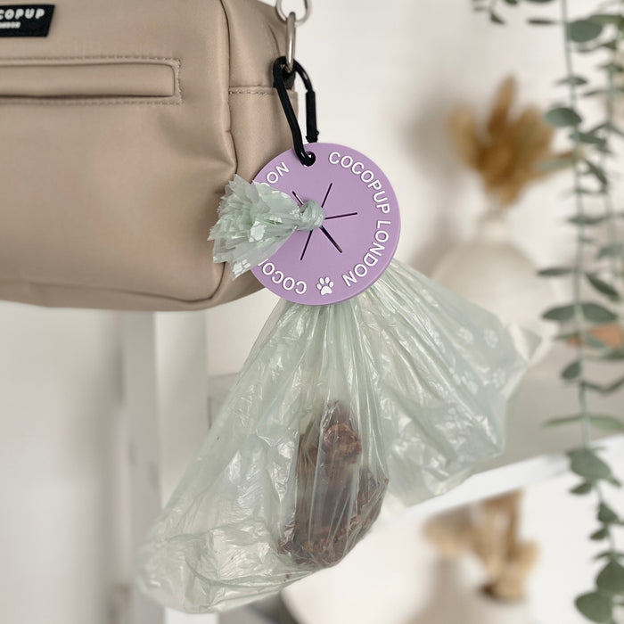 Purple CocoPOOP Pocket by Cocopup London clipped to a beige bag, featuring a compact, hands-free design.
