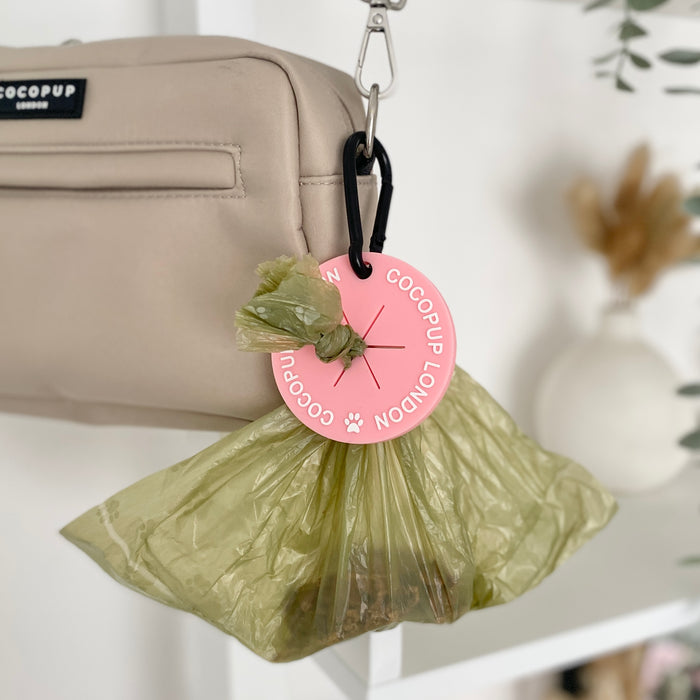 Pink CocoPOOP Pocket by Cocopup London clipped to a beige bag with gold hardware.