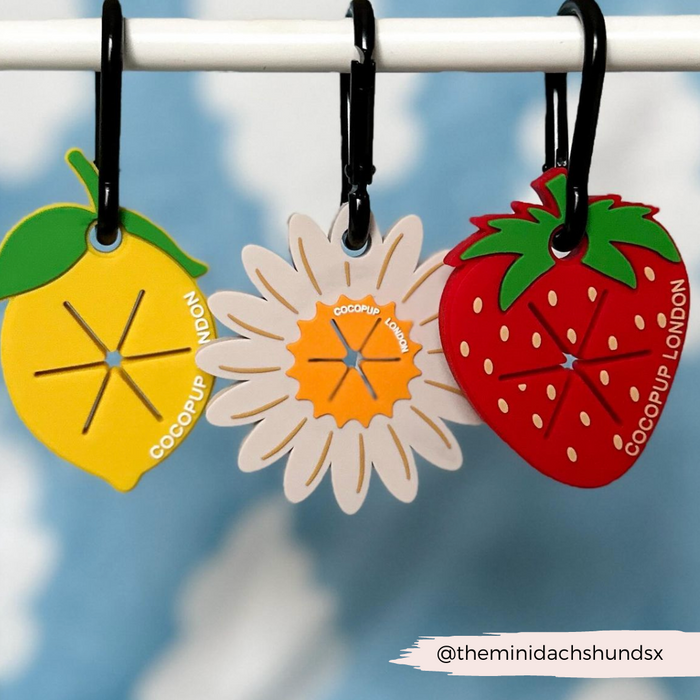 Three red strawberry-shaped tags with green tops by Cocopup London, designed to clip onto a CocoPOOP Pocket.