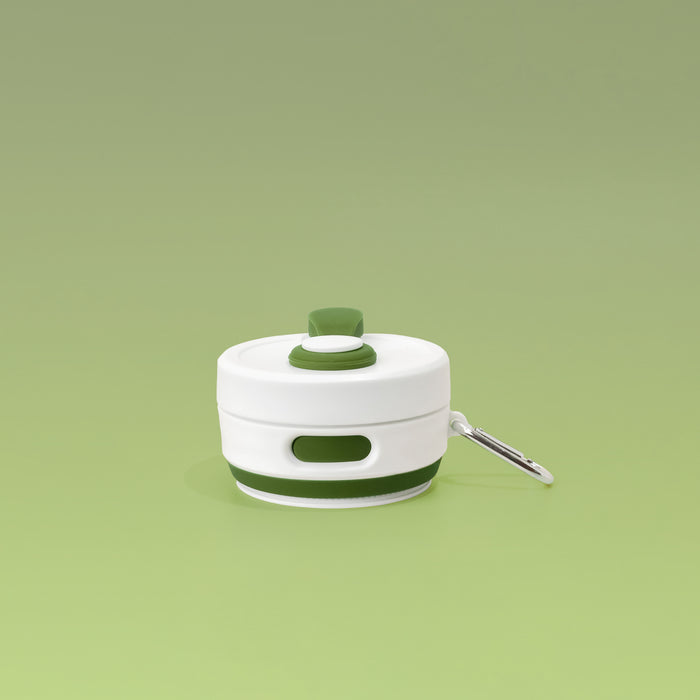 Collapsed view of Plain Khaki with White Lid Collapsible Silicone Travel Coffee Cup with Cocopup branding and carabiner clip.