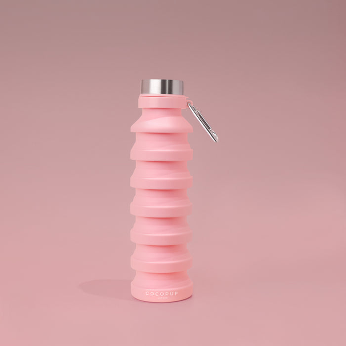 Pink Cocopup London collapsible silicone water bottle standing upright on a matching pink background.