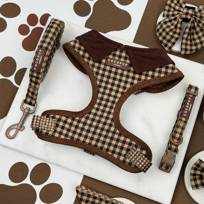 Cotswold Check harness, lead, and collar set with bow tie in beige plaid, displayed on marble with paw print accents.