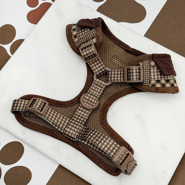Cotswold Check harness, lead, and collar set in beige plaid on white marble background with brown paw prints.