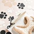 Cream quilted dog lead and matching harness on a tray with black and beige paw print decorations.