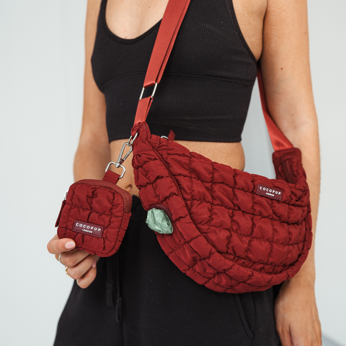 Woman in black crop top holds a maroon Cocopup treat pouch and matching quilted dog walking bag.