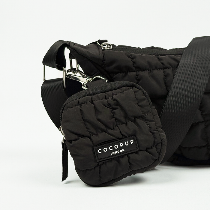 Black quilted treat pouch with a crescent shape, designed for dog walking.