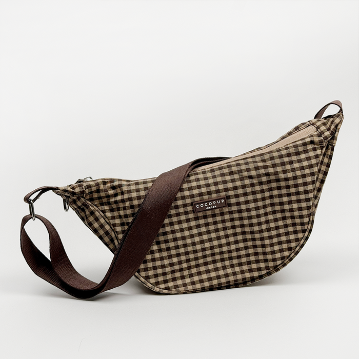Crossbody crescent dog walking bag in Cotswold check plaid fabric with adjustable strap and zip closure.