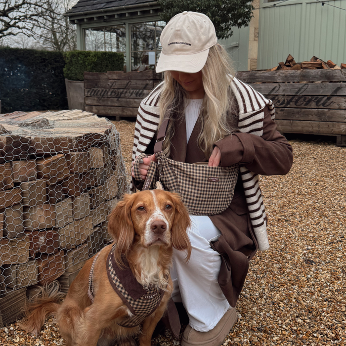 Woman and dog in matching beige check accessories with a tan Cocopup London crossbody dog walking bag.