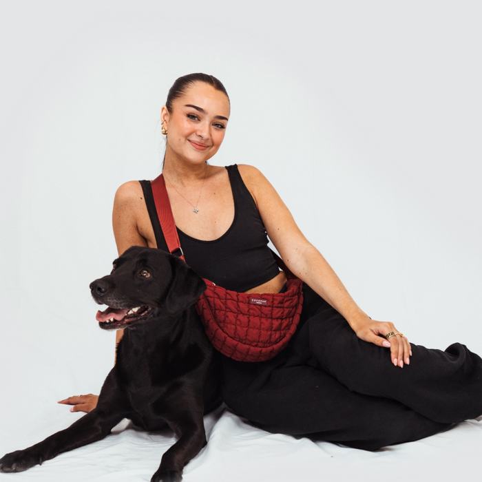 Woman with her dog wearing a Merlot Cocopup London Crossbody Crescent Dog Walking Bag.