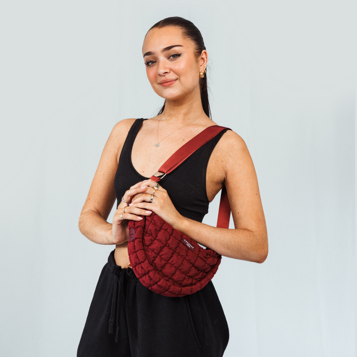 Woman wearing a merlot Cocopup London crossbody dog walking bag, standing against a plain light background.