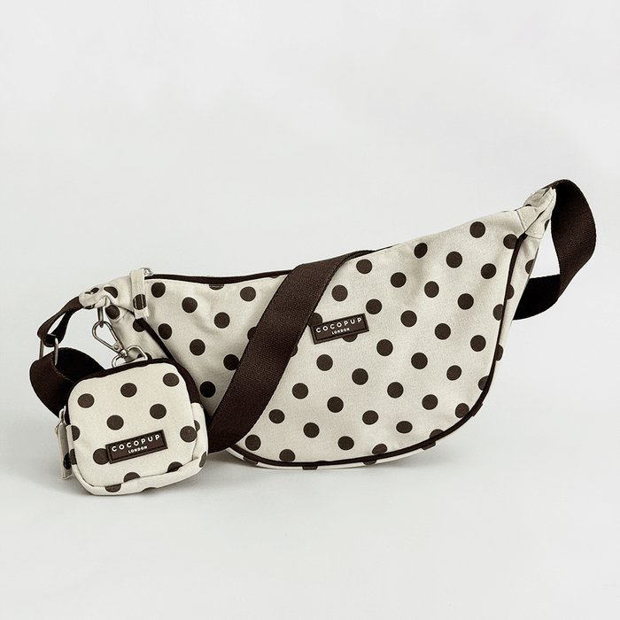 Polka dot crossbody bag with matching pouch on a light gray background