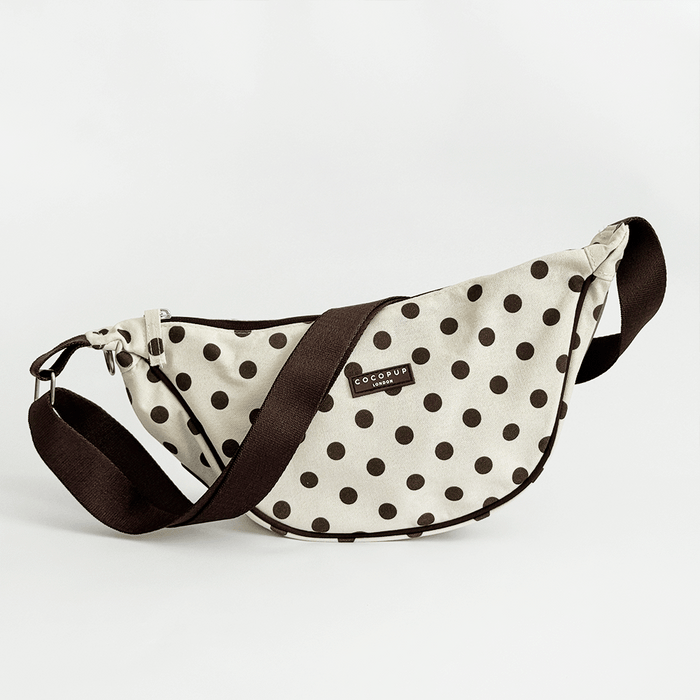 Polka dot waist bag with brown strap on a light gray background