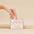 Hand holding Cocopup London Daisy Chain Card Holder, floral patterned, against beige background with pampas grass.
