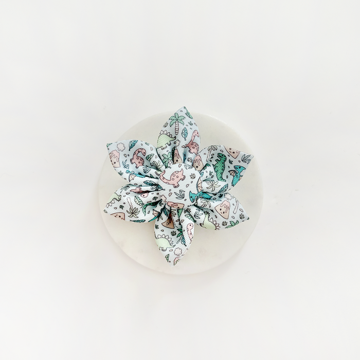 Dinosaur print bow collar accessory in bright colors, clipped to a white round display card.
