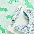 Light blue Cocopup London dog lead featuring a dinosaur pattern, shown with green dino and palm tree cutout props.