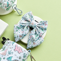 Pastel dinosaur-patterned Cocopup London sailor bow tie on a stand with a pale green background.