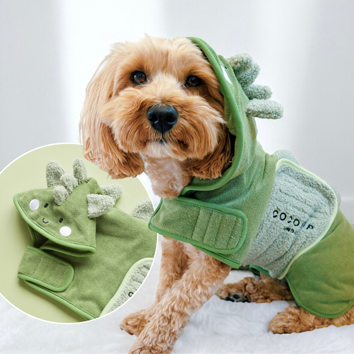 Dog in a Cocopup London Dinopup green drying robe with plush spikes and a hood featuring a smiling face.