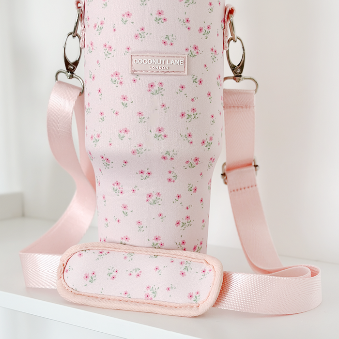 Pink tumbler carry case with ditsy floral pattern, padded strap, and metal clips by Cocopup London.