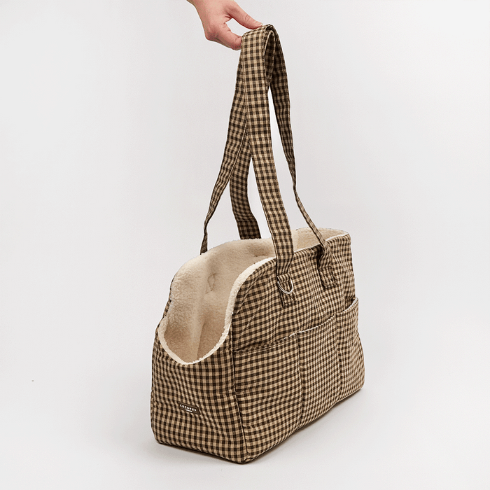 Brown check print Dog Carrier with a cream sherpa fleece lining, featuring a side pocket with white piping, and a small silver-tone metal ring detail.
