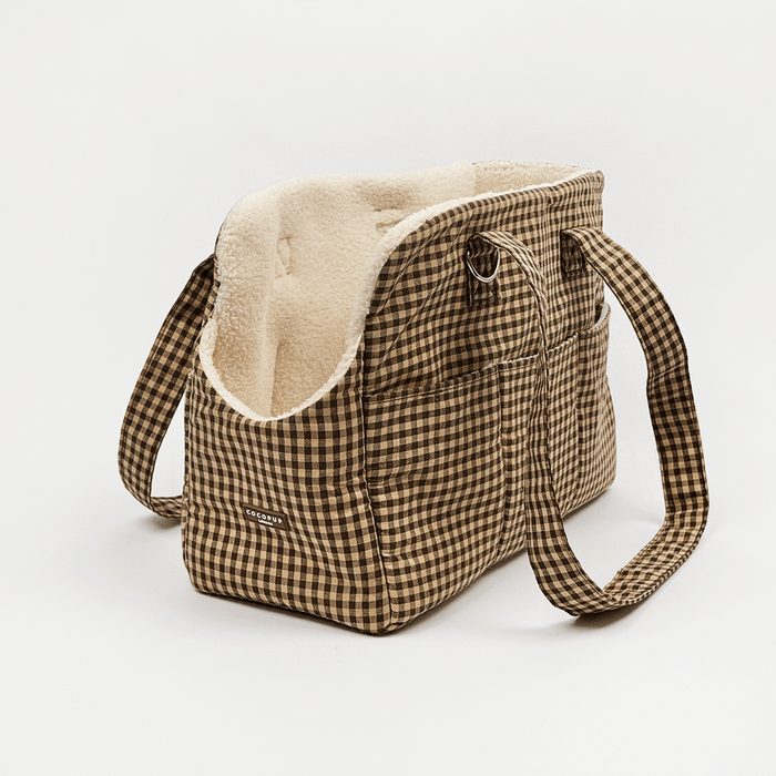Brown check print Dog Carrier with a cream sherpa fleece lining, featuring a side pocket with white piping, and a small silver-tone metal ring detail.