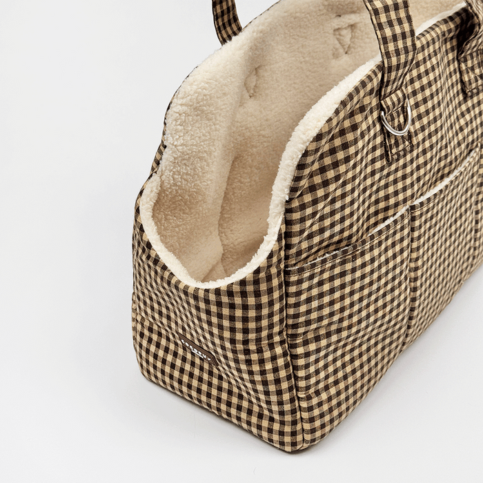Brown check print Dog Carrier with a cream sherpa fleece lining, featuring a side pocket with white piping, and a small silver-tone metal ring detail.