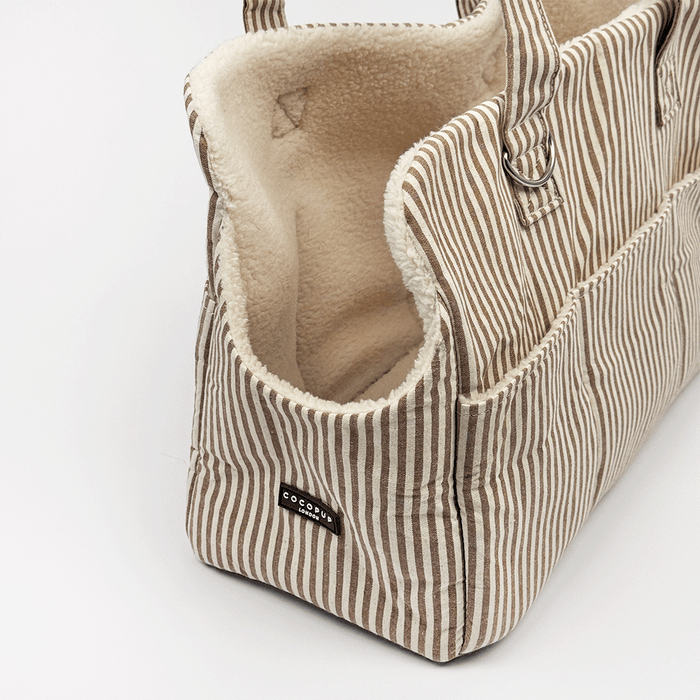 Brown and cream stripe Dog Carrier with a cream sherpa fleece lining, featuring a side pocket with white piping, and a small silver-tone metal ring detail.