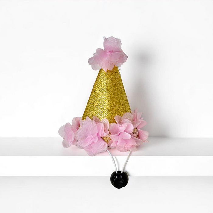 Pink dog party hat from Cocopup London with glittery details and pink flower accents.