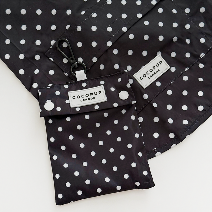 Black polka dot dog raincoat with matching pouch, both made of lightweight material.