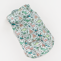 Light blue Cocopup London dog raincoat with dinosaur, palm tree, and volcano print, displayed on a white background.
