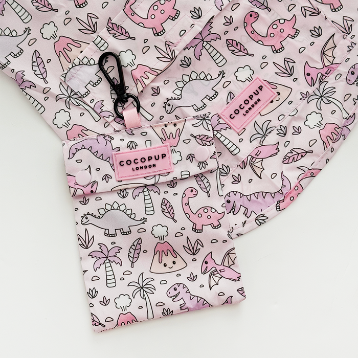 Pink and white Cocopup London dog raincoat with cartoon dinosaur print. Lightweight material.