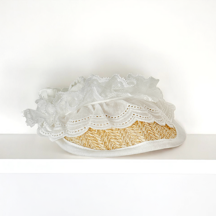 Cocopup London dog sun hat made of straw with lace trim, displayed on a white shelf against a plain white background.