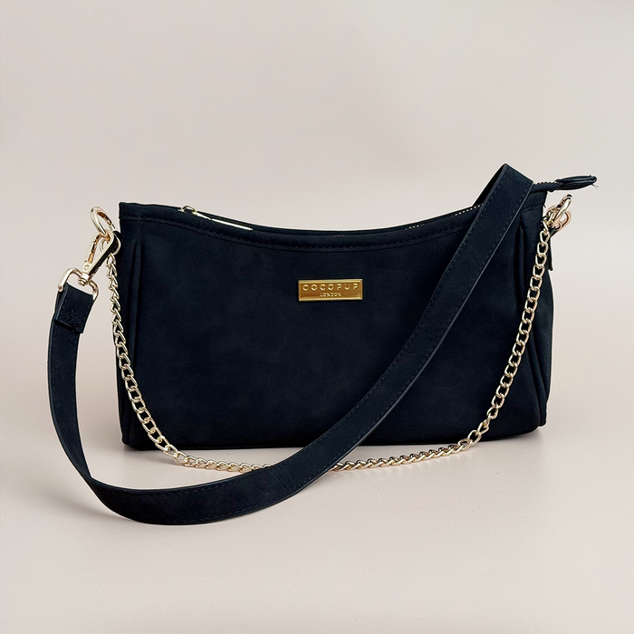 Black suedette Cocopup London dog walking bag with gold chain strap, logo plate, and built-in poop bag dispenser.