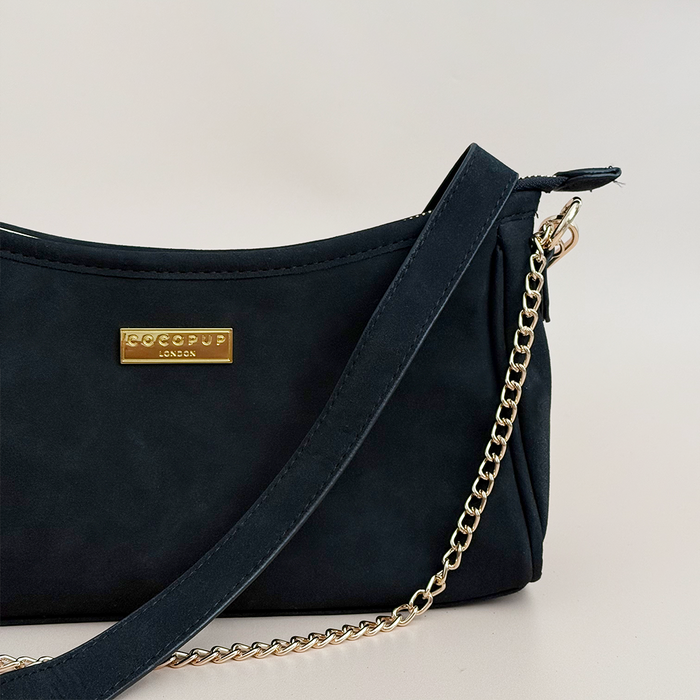 Black suedette dog walking bag with gold chain strap and visible built-in poop bag dispenser.
