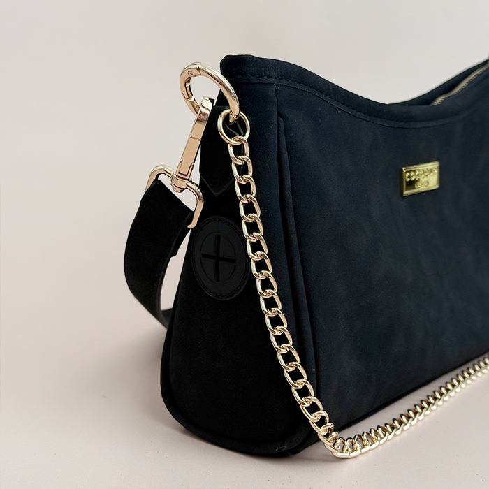 Black suedette Cocopup London dog walking bag with gold chain strap and hidden dispenser, shown on a light background.