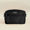 Small black Cocopup London dog walking bag with front zipper and poop bag dispenser on a beige background.