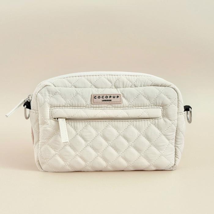 Cream quilted dog walking bag with front zipper pocket and adjustable strap.