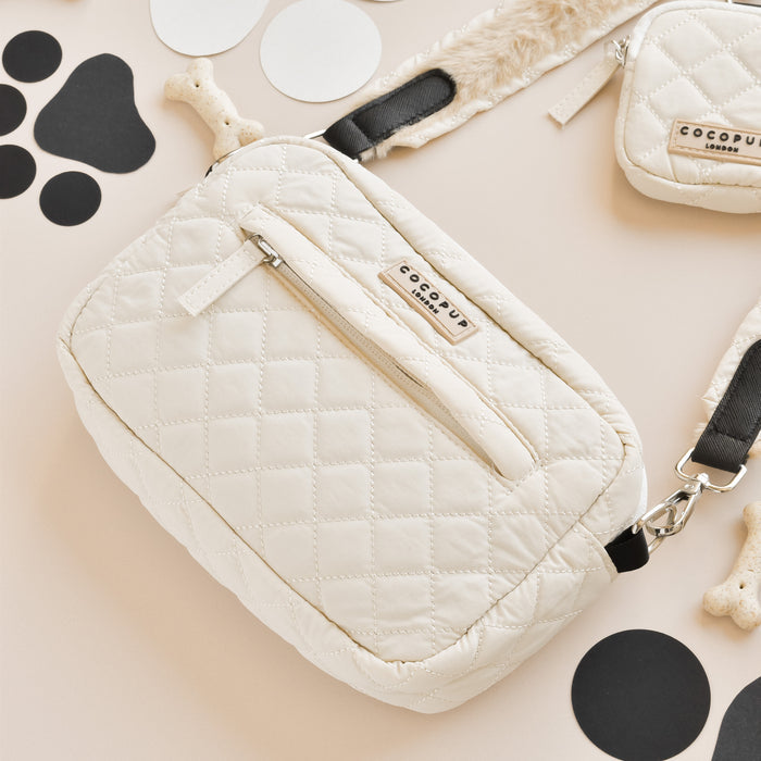 Cream quilted dog walking bag with a black strap by Cocopup London, displayed with dog walking essentials.