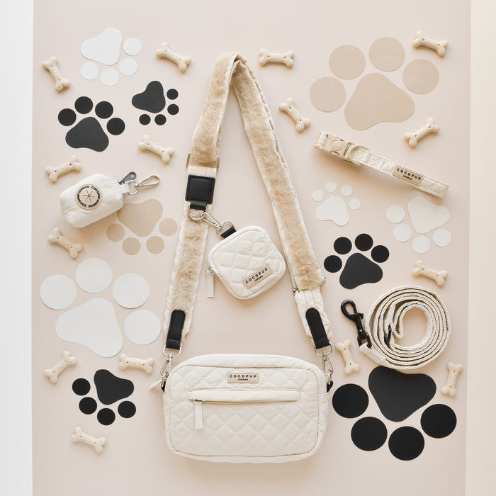 Cream quilted dog walking bag with paw print and bone pattern, paired with a matching cream poop bag dispenser.