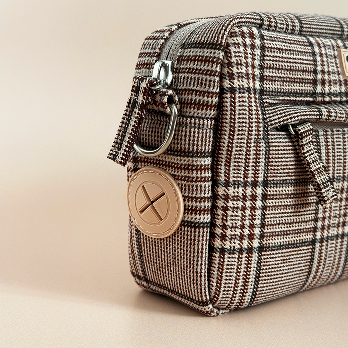 Cocopup London dog walking bag in pup plaid with a beige and gold round keychain on a neutral background.