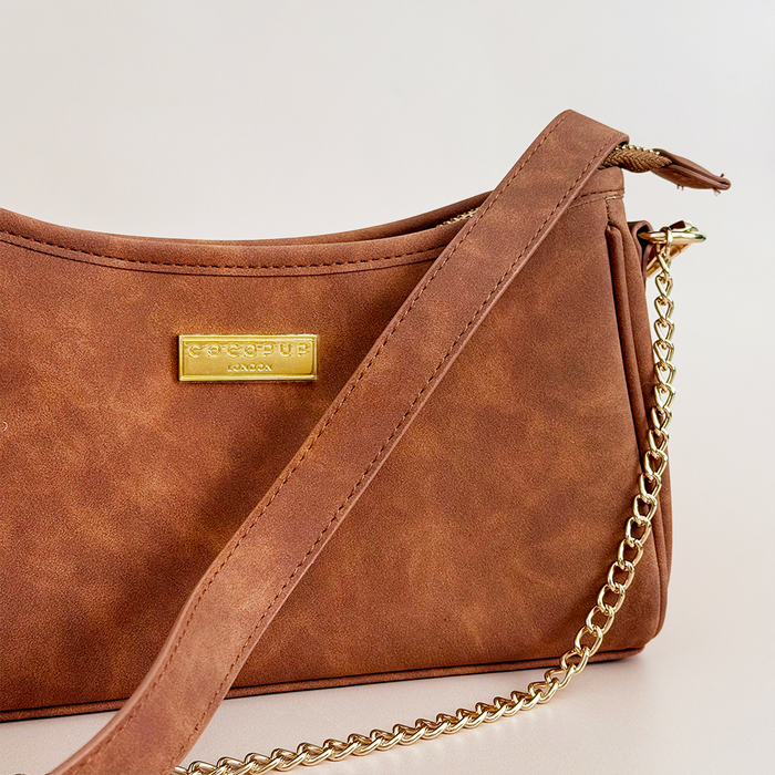 Tan suedette dog walking bag with gold chain strap and front label, designed as a poop bag dispenser.