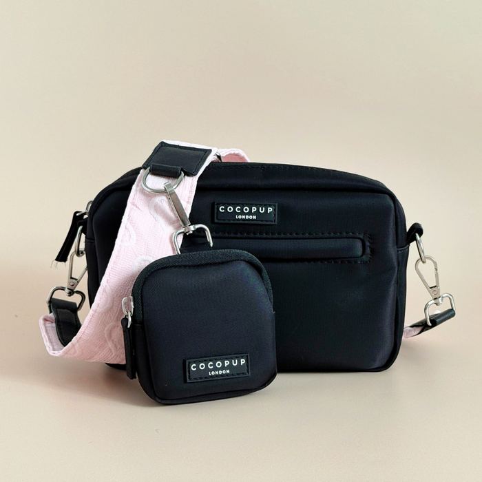 Two black Cocopup London dog walking bags with silver hardware and baby pink heart-patterned straps.