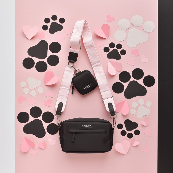 Baby pink Cocopup London dog walking bag with heart design, shown on a pink background with paper hearts and paw prints.