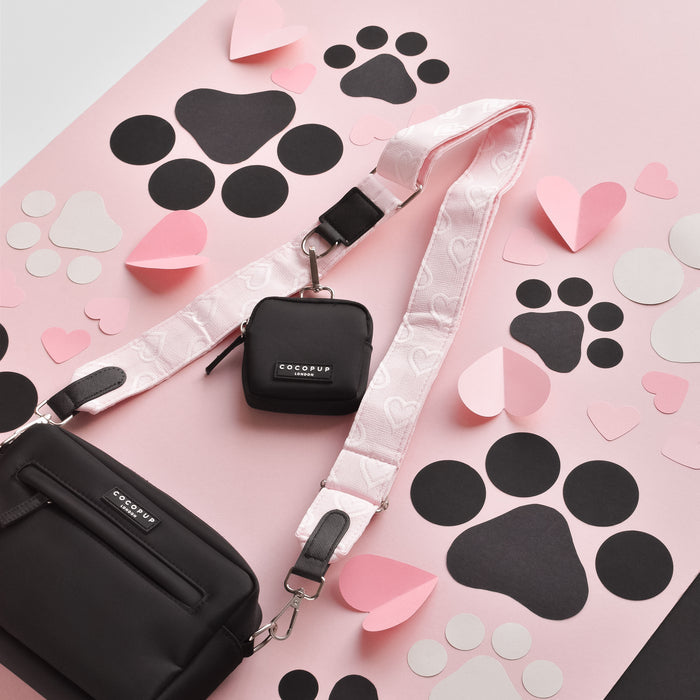 Baby pink dog walking bag bundle with heart cutouts, matching treat pouch, pink strap, and paw print accents.