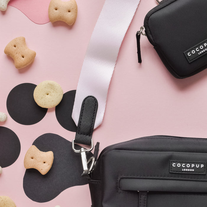 Baby pink Cocopup London dog walking bag with treats and a white strap, displayed on a pink spotted background.