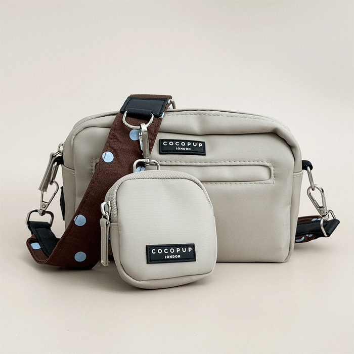 Beige Cocopup Dog Walking Bag, with small pouch for treats attached and also a brown bag strap with blue polka dots.