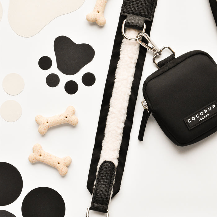 Black Cocopup London dog walking bag with matching leash, treat pouch, bone treats and paw cut-outs on white background.